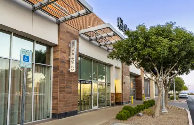 Exterior of a modern commercial building with large windows, a Chai House sign, and a reserved accessible parking sign. Trees and landscaping line the storefront, with Sparkles Beauty Bar also located nearby for added convenience.