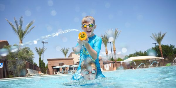 two boys playing in pool in Summerlin with a squirt gun