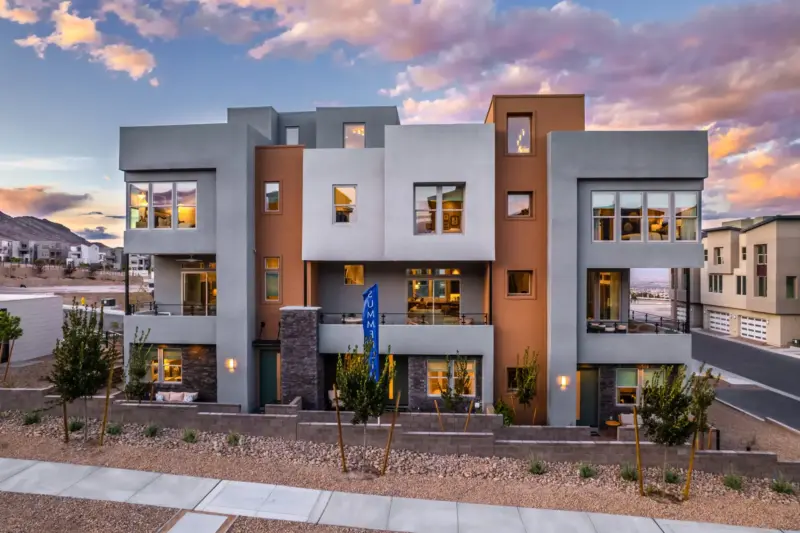 Modern three-story Toll Brothers homes in Summerlin with stucco and stone exteriors at dusk, an example of the new construction builders are lining up in the community