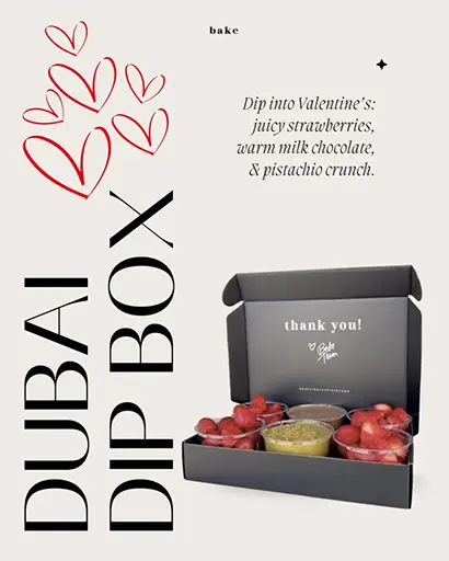 A black box labeled thank you! is open, revealing fresh strawberries, milk chocolate dip, and pistachio topping. The text reads: Dubai Dip Box. Dip into Valentine’s: juicy strawberries, warm milk chocolate, & pistachio crunch. Red heart doodles are on the left.