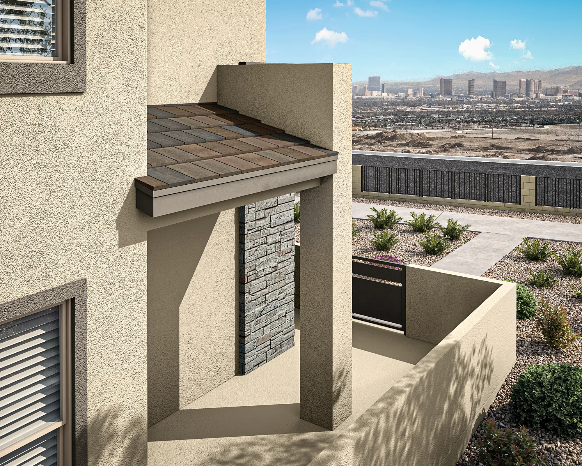 11_TP-LV-Aberdeen_Collection_ONE_HT_P1A-Addl_Cam_2_CS_03_bowoww A modern beige house features a stone accent wall, a brown shingle roof overhang, and a small patio area with desert landscaping. In the distance, a city skyline and mountains are visible under a blue sky with clouds.