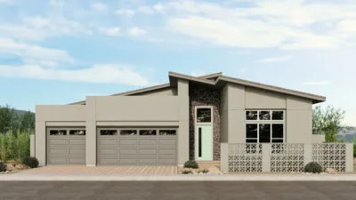 Modern single-story house with a flat, sloped roof, large garage doors, a tall front door with glass panels, stone and concrete exterior, and a decorative concrete screen wall in front. Desert landscaping surrounds the home.