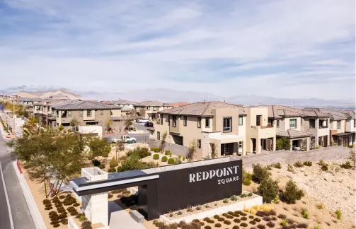 A residential neighborhood with modern two-story houses and landscaped yards, featuring a large entrance sign that reads REDPOINT SQUARE under a partly cloudy sky.