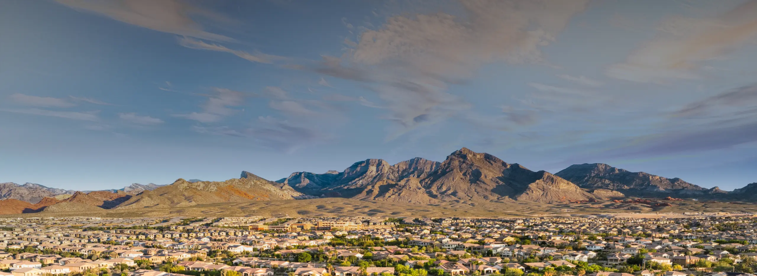 Wide view of Summerlin rooftops stretching to the base of the mountains on the west edge of the Las Vegas Valley, where builders are buying new home land