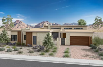 Modern single-story house with stone and wood accents, desert landscaping, and mountain range in the background under a clear blue sky.