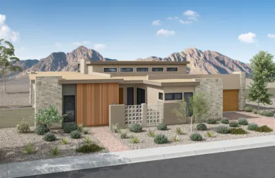 Modern desert home with stone and wood accents, flat roof, large windows, gravel landscaping, desert plants, and mountain scenery in the background under a clear blue sky.