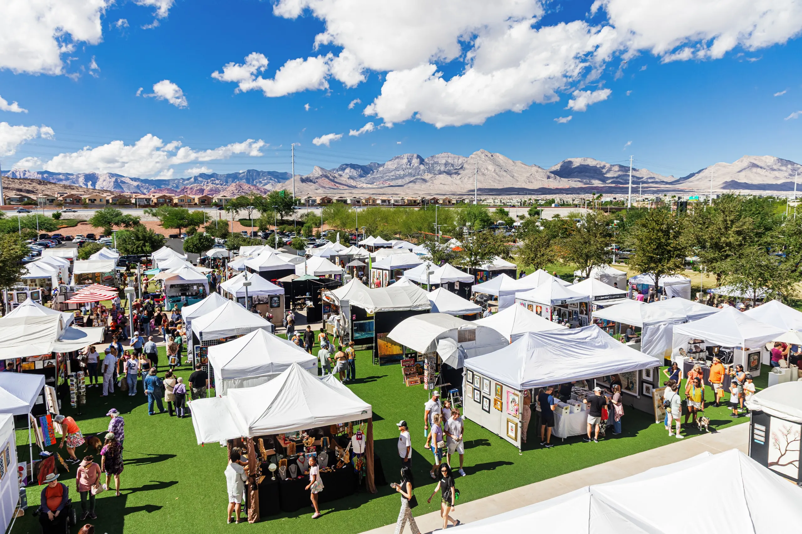 Aerial view of white artist booth tents on The Lawn at Downtown Summerlin during the 2025 Summerlin Festival of Arts, with the Spring Mountains in the background
